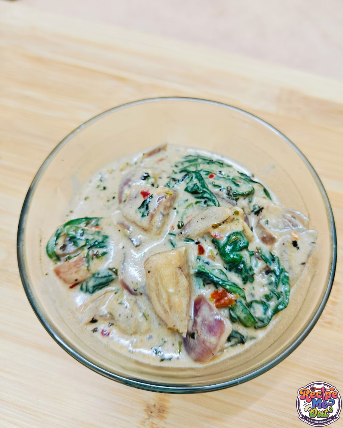 Creamy spinach Alfredo served in a glass bowl, showing spinach and onion pieces in thick sauce.