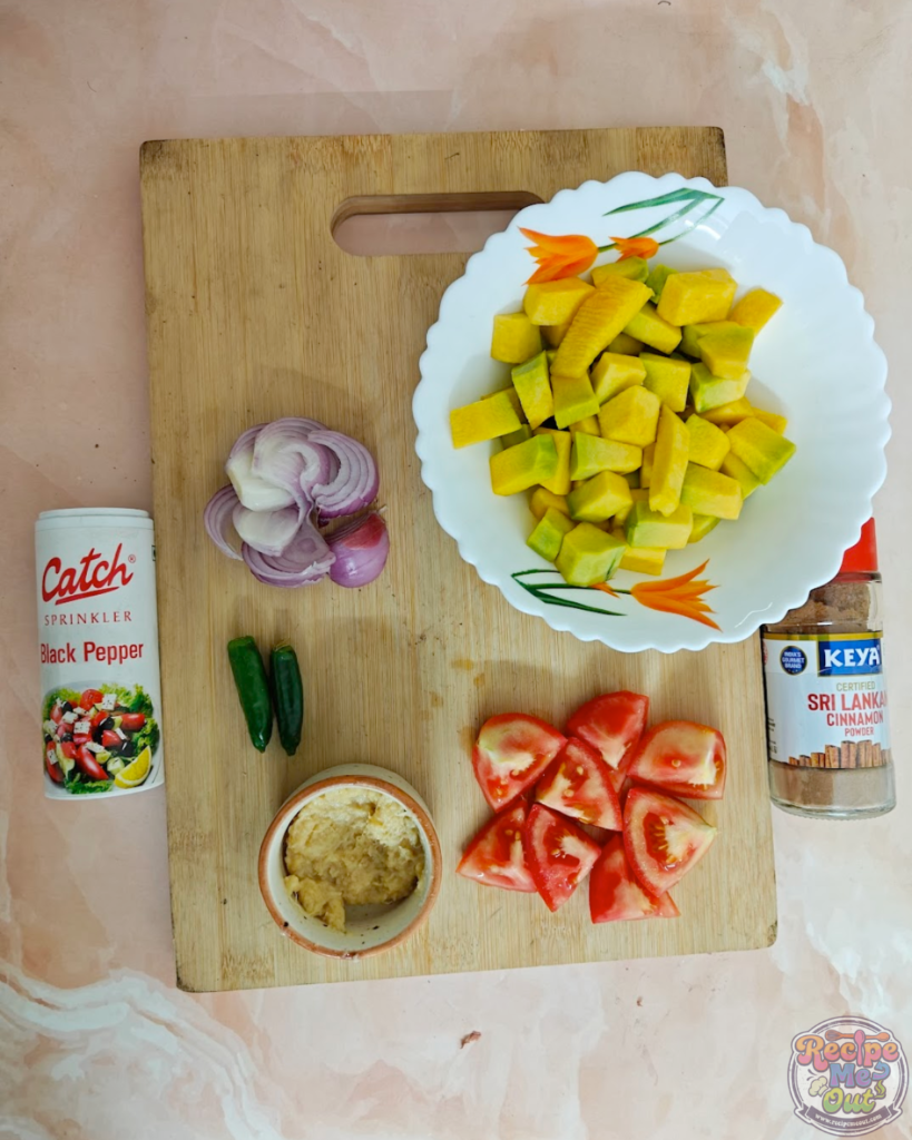 All pumpkin pasta ingredients arranged on a board, including diced pumpkin, tomatoes, onions, garlic, green chillies, cinnamon powder, black pepper
