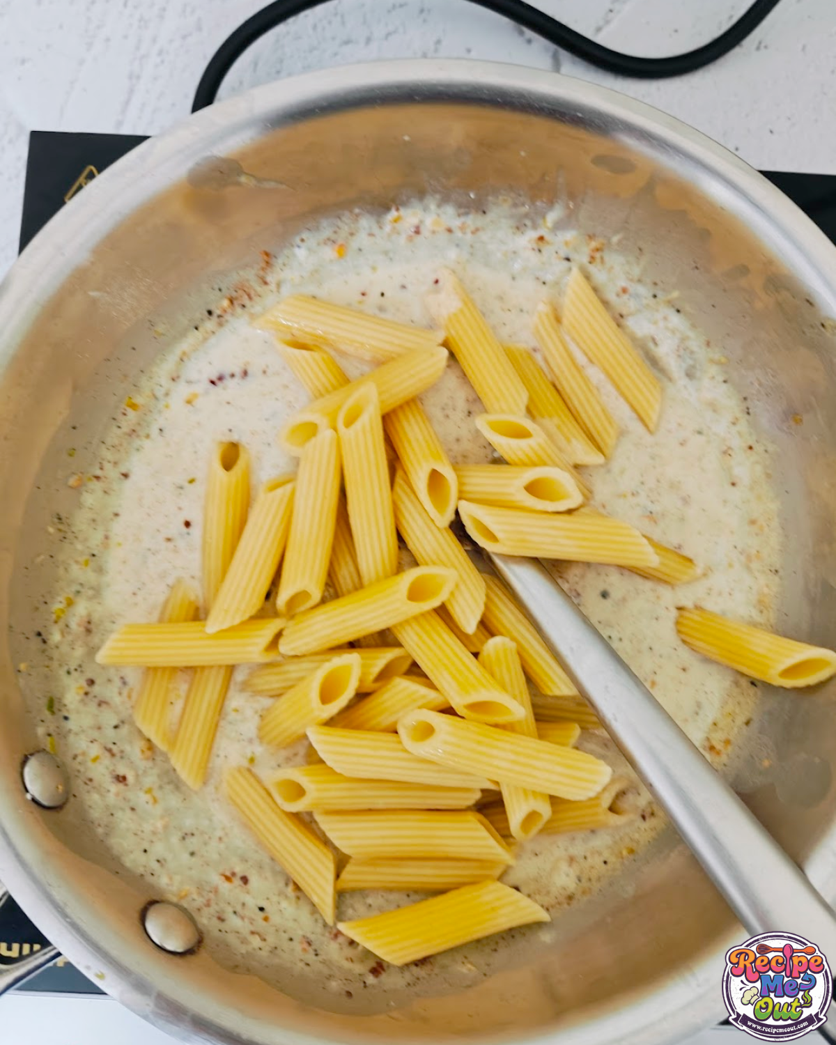 Cooked penne pasta added into the creamy garlic sauce.
