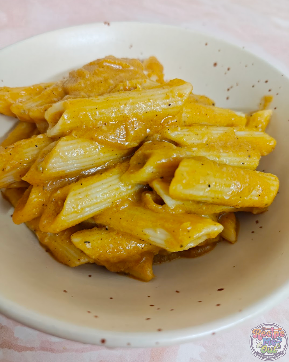 Closeup shot of pumpkin pasta served hot, showing sauce coating the penne evenly.