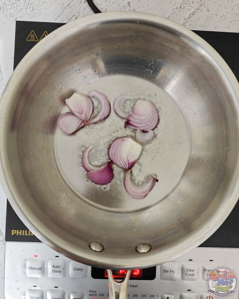 Sliced onions added to hot oil in a pan, beginning the sautéing process for the sauce.
