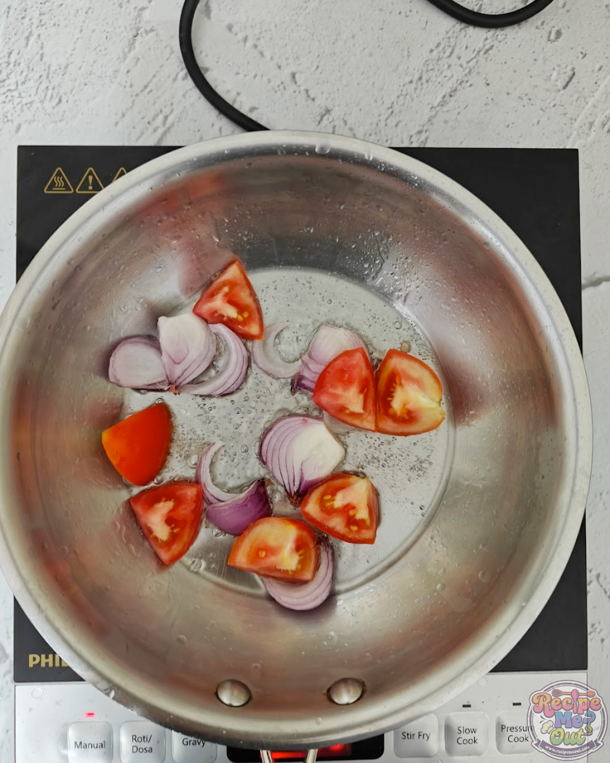 Chopped tomatoes added to sautéed onions in a pan while cooking the base of the pumpkin pasta sauce.