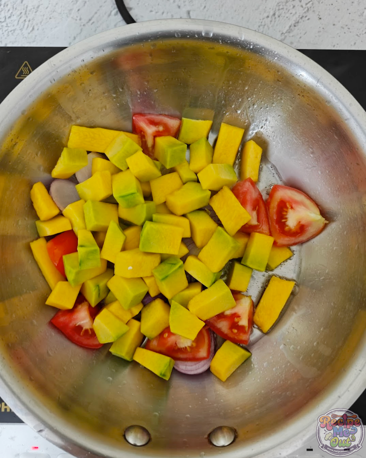 Diced pumpkin added to the pan with onions and tomatoes, cooking together with salt.