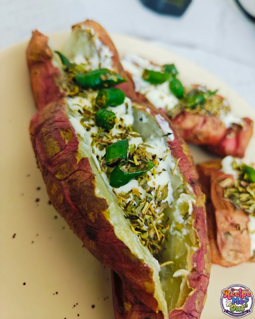 A close-up of an Air-Fried Sweet Potato cut open and generously filled with gooey melted cheese, vibrant green chilies, and a sprinkle of dried herbs, served hot.