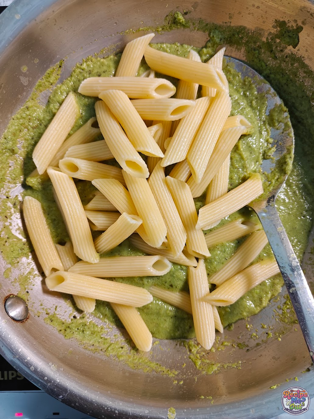 Cooked penne pasta added to green peas sauce in pan