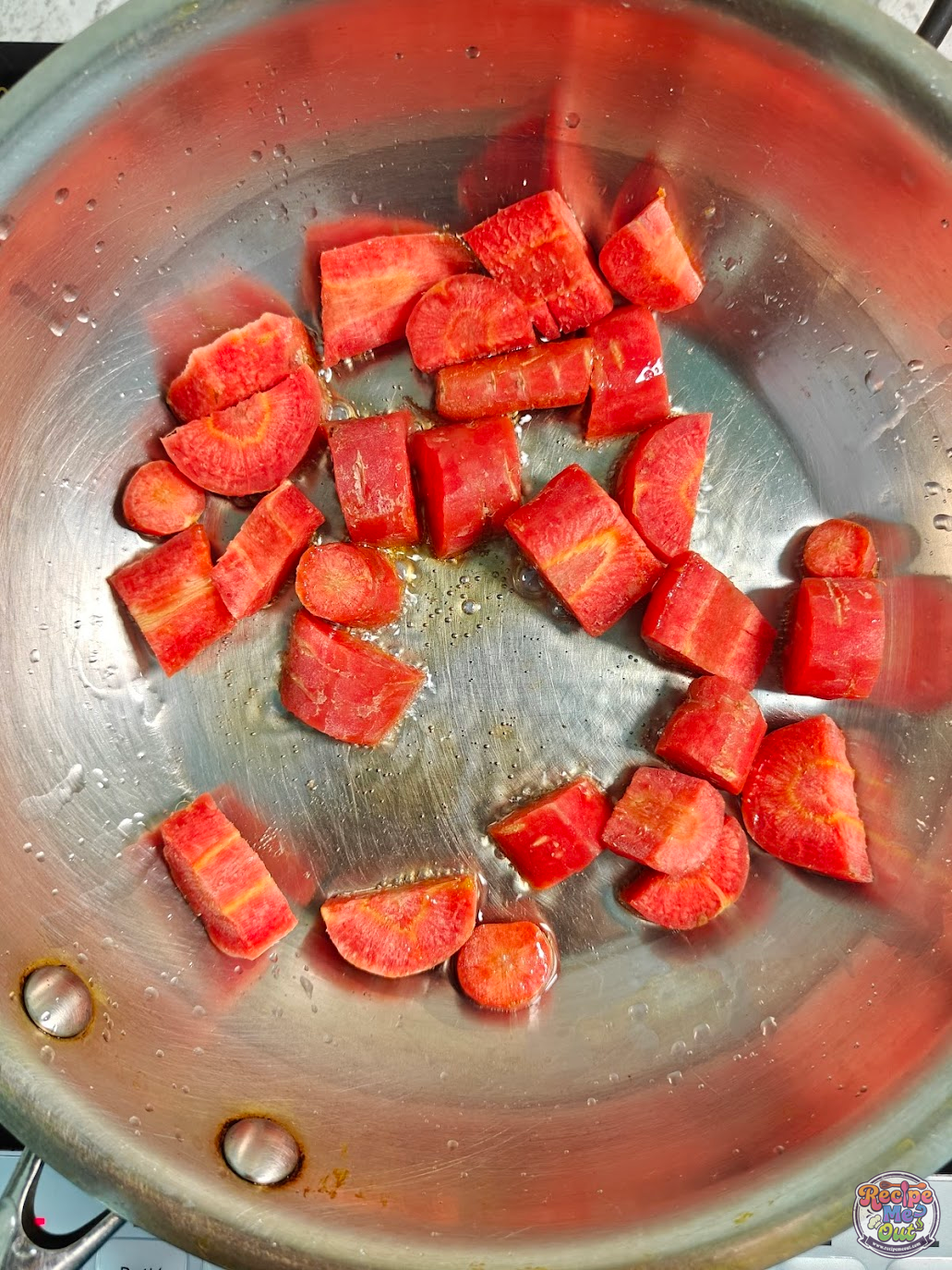 Chopped carrots starting to get sautéd in oil in a pan until partially cooked to form the base for carrot pasta sauce.