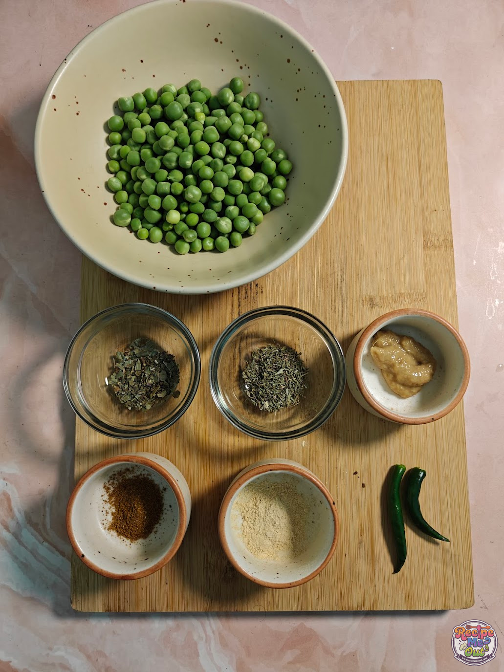 Ingredients for Green Peas Pasta including fresh green peas, herbs, spices, ginger paste and green chillies on a board