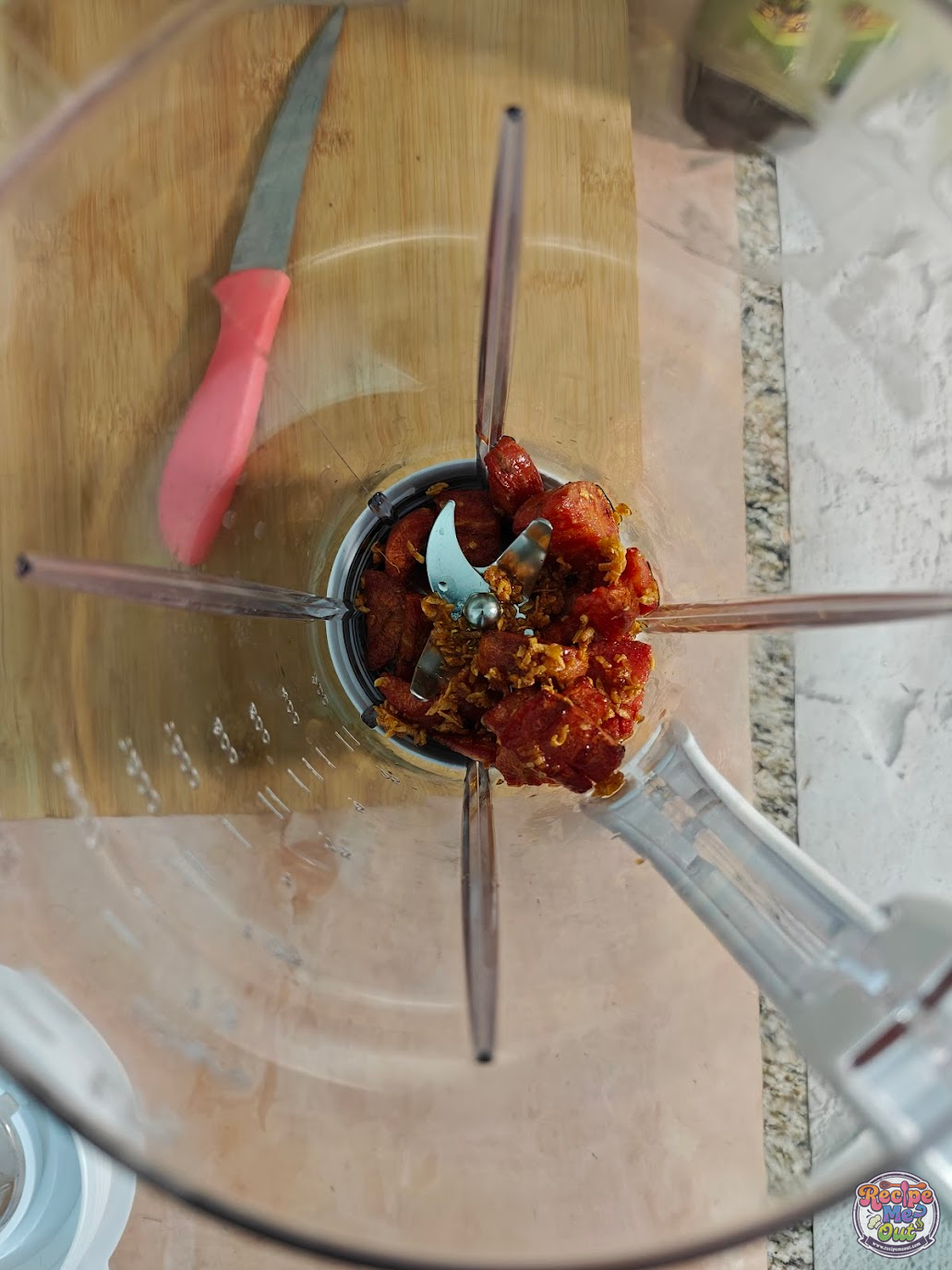 Blended carrot sauce cooking in a pan with milk and spices including cayenne pepper, red chilli flakes, and cinnamon powder.