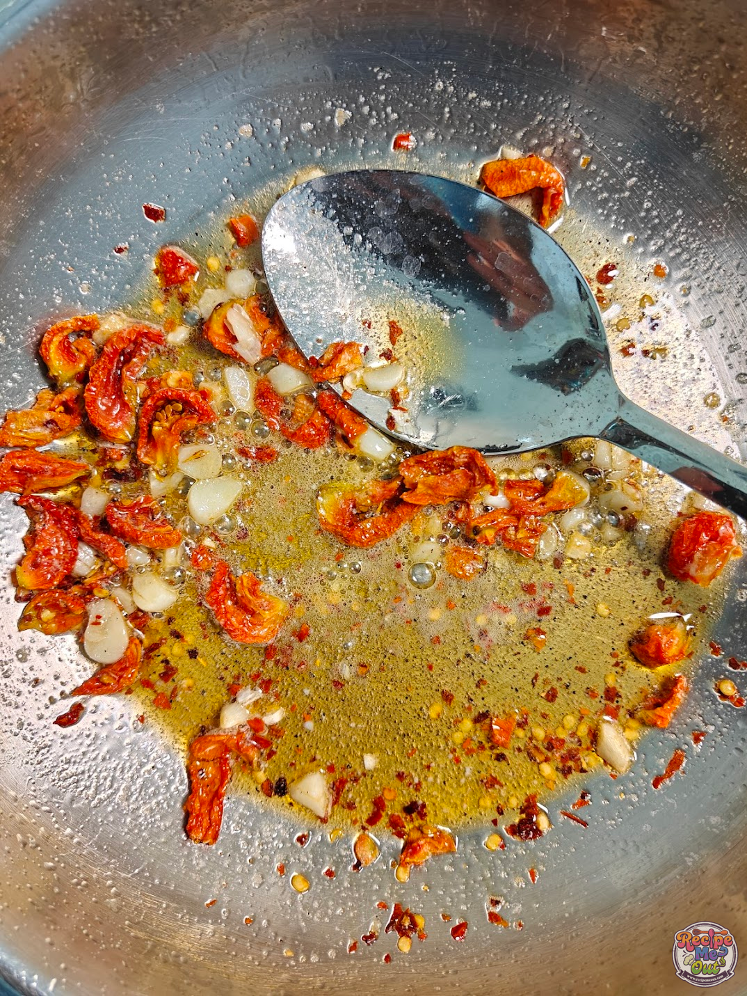 Garlic, sun-dried tomatoes, chilli flakes, and black pepper cooking together