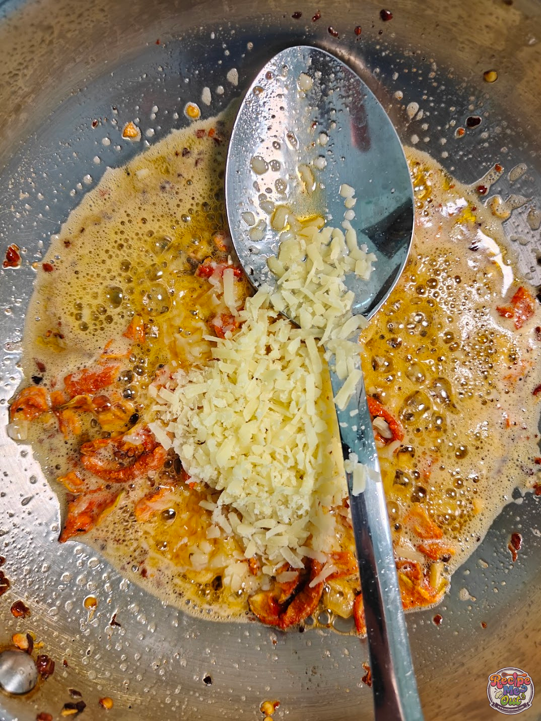 Grated Parmesan cheese being added into the pan mixture