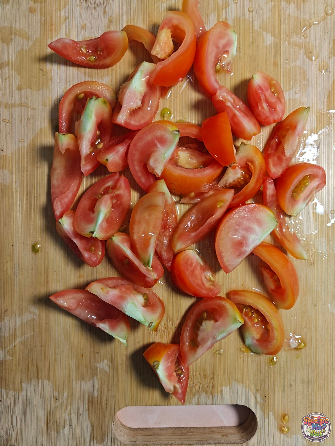 Tomatoes cut into wedges on a wooden board, showing juicy interiors and seeds before seasoning.