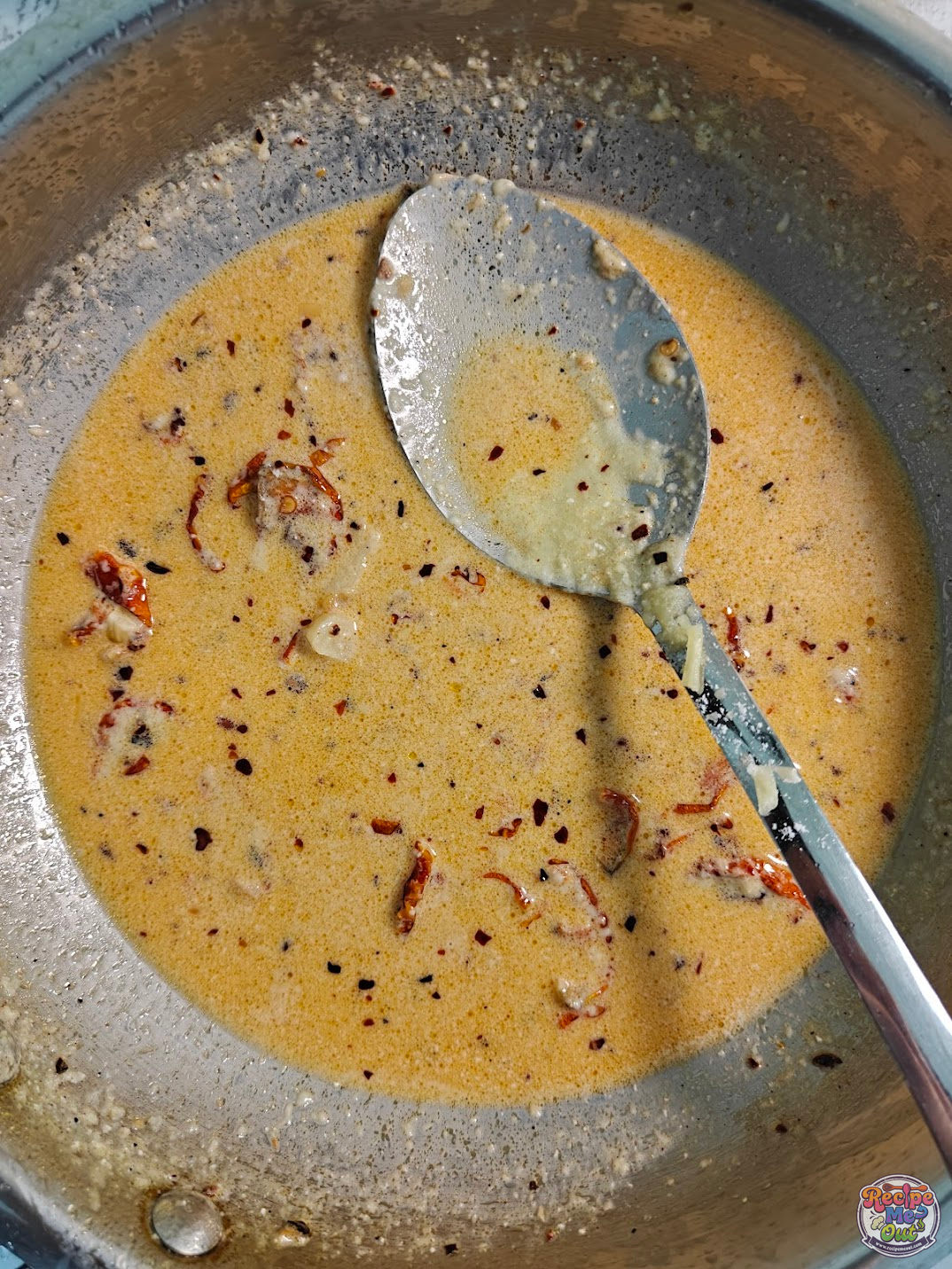 Creamy sauce mixed smoothly with spices and sun dried tomatoes in pan