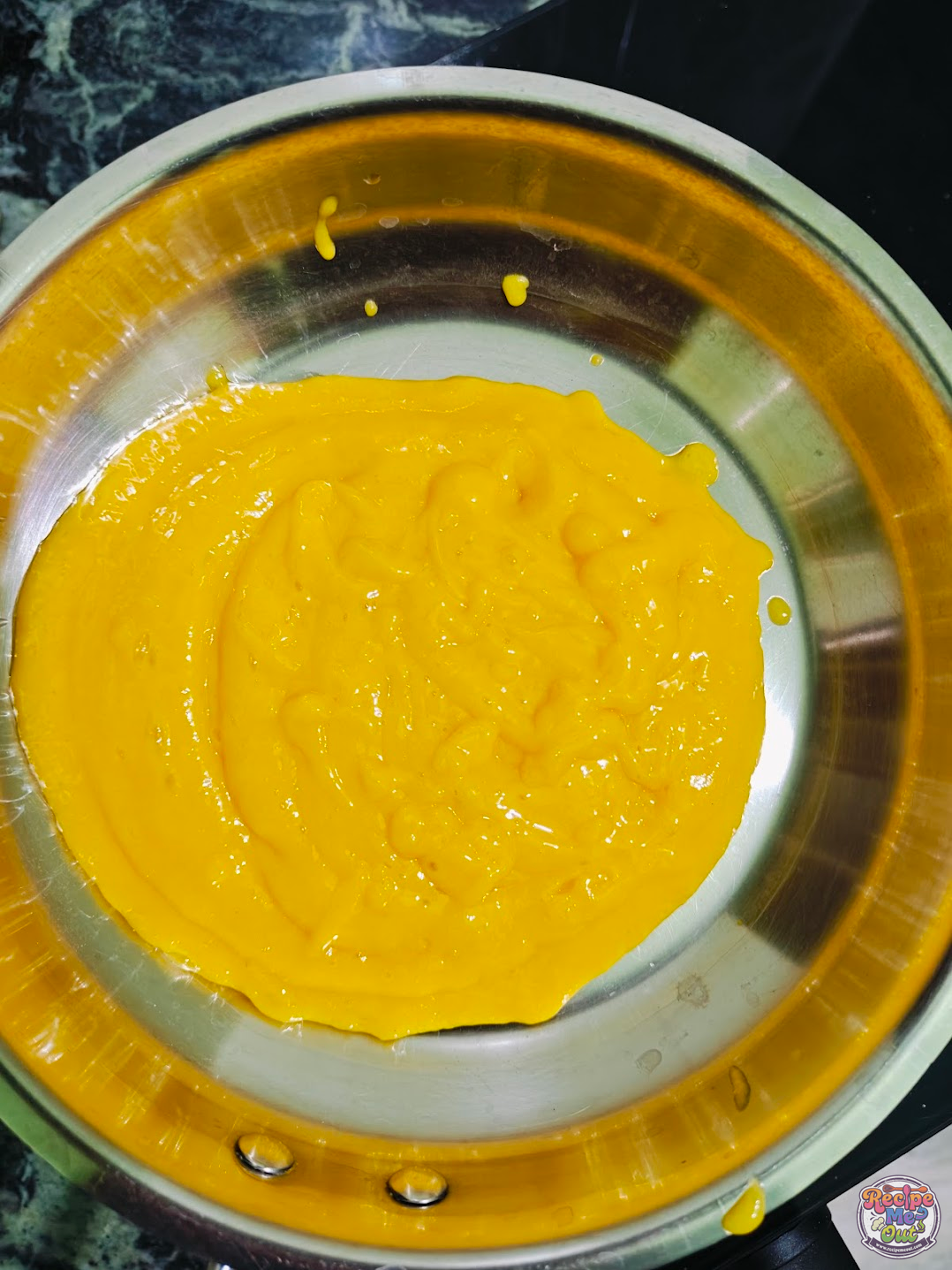 Fresh mango puree cooking in a skillet until smooth and slightly thickened.
