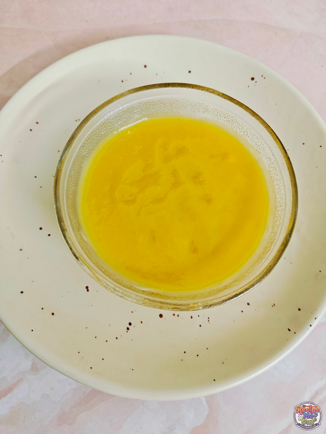 Freshly prepared mango pudding poured into a glass dessert bowl before chilling.