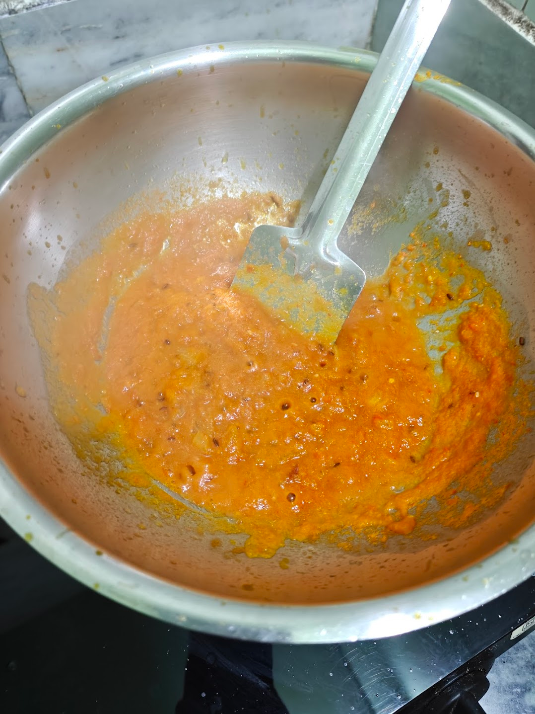 Spiced tomato onion masala cooking until thick in a pan.