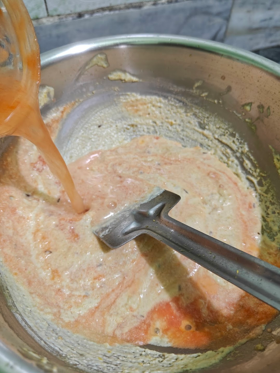 Tomato puree being mixed into the white sauce mixture