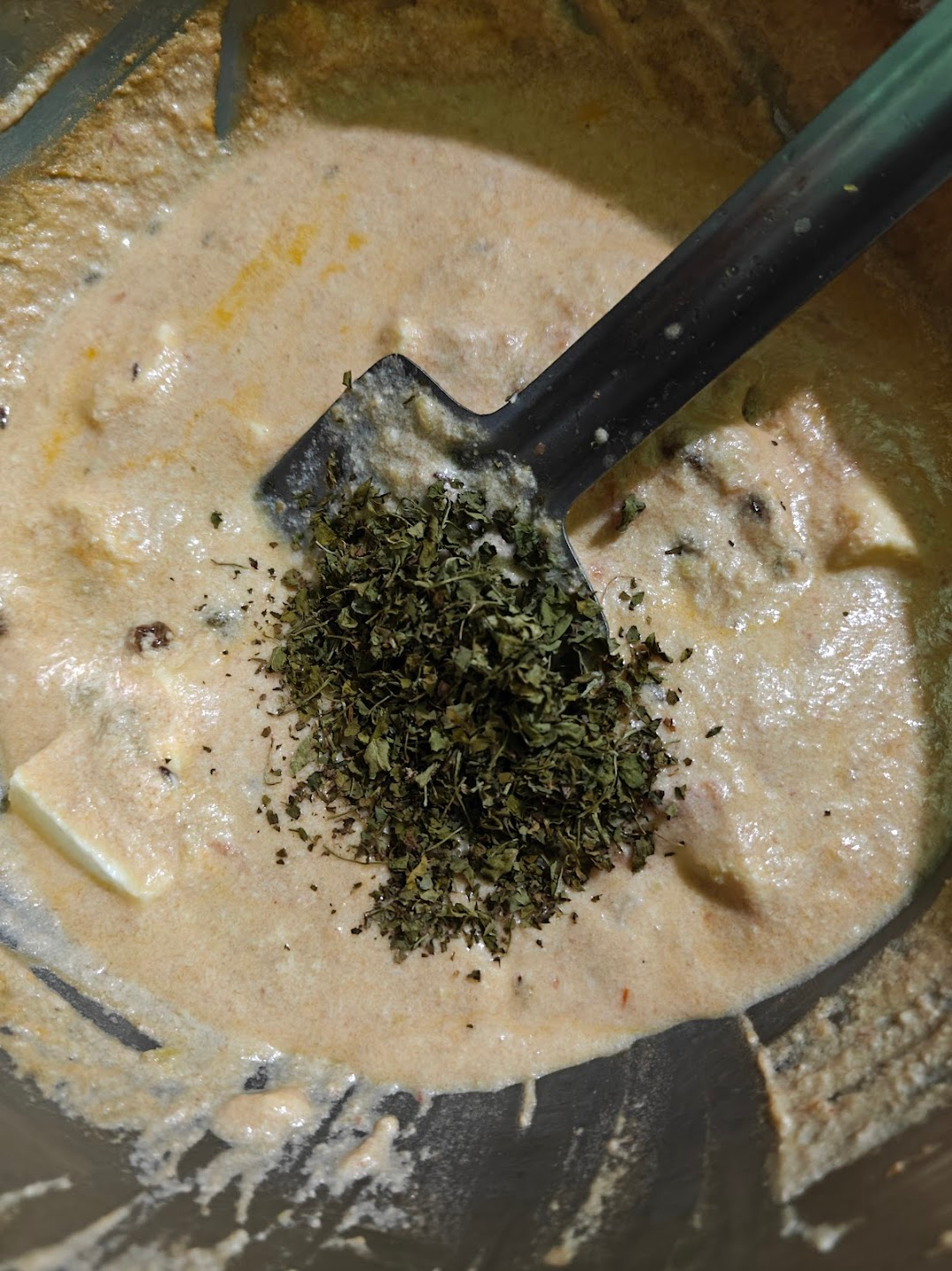 Crushed and dry roasted kasuri methi being added to paneer in white sauce.