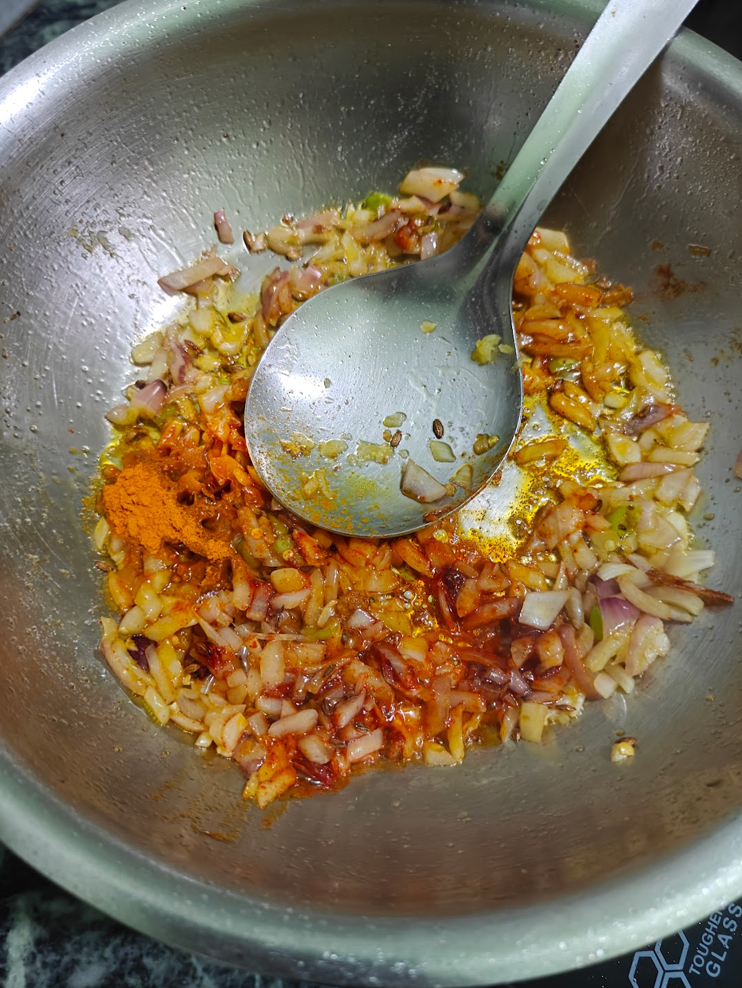 Cooking onions with red chilli powder for Achari Aloo
