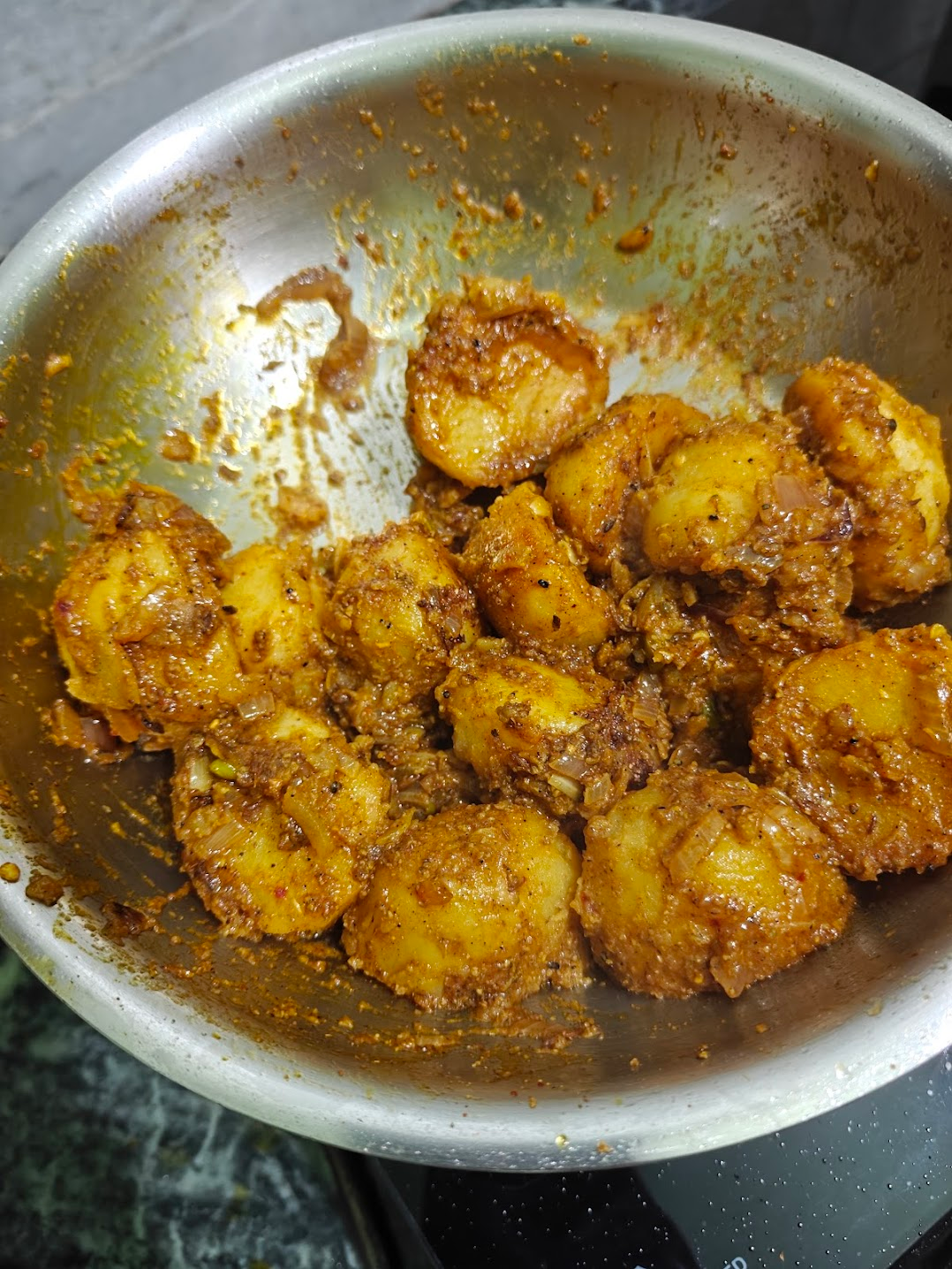 Potatoes coated with thick achari masala in a pan