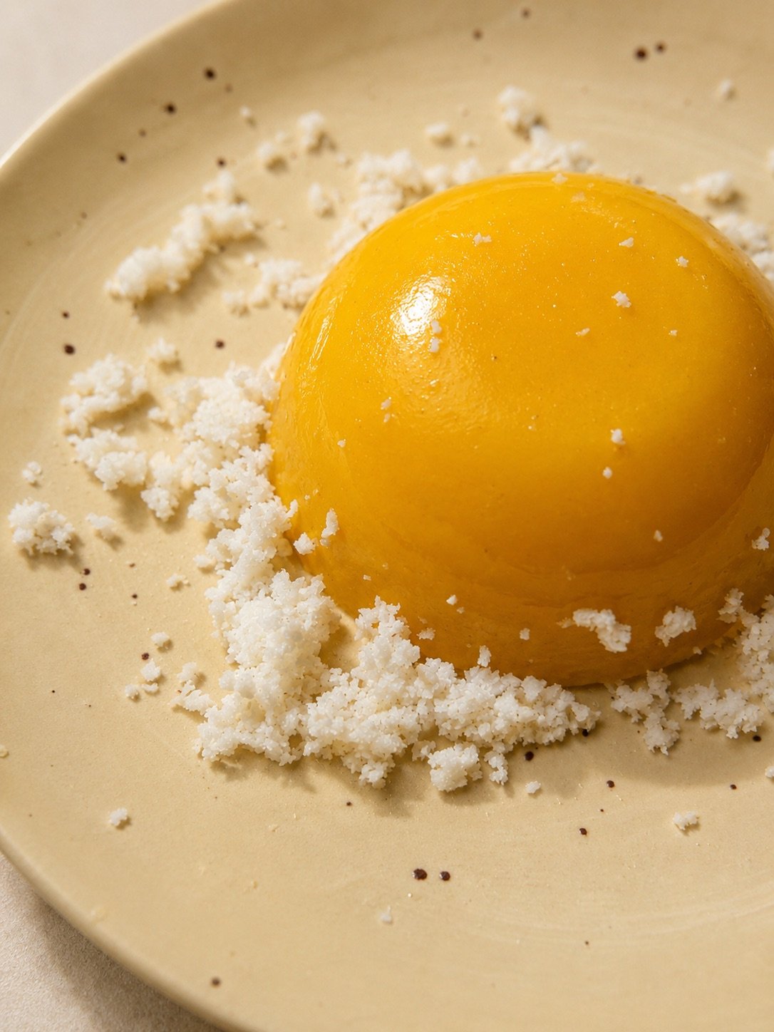 A close-up shot of creamy Coconut Mango Pudding served in plate, topped with freshly grated coconut flakes.
