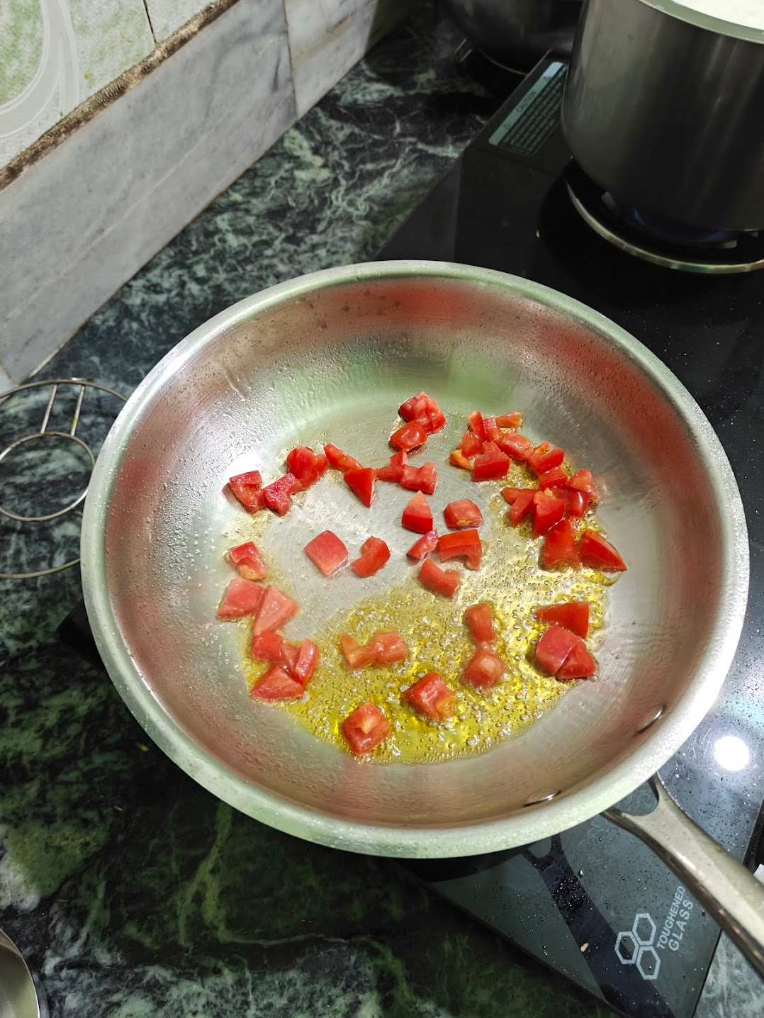 Chopped tomatoes cooking in oil in a stainless steel pan
