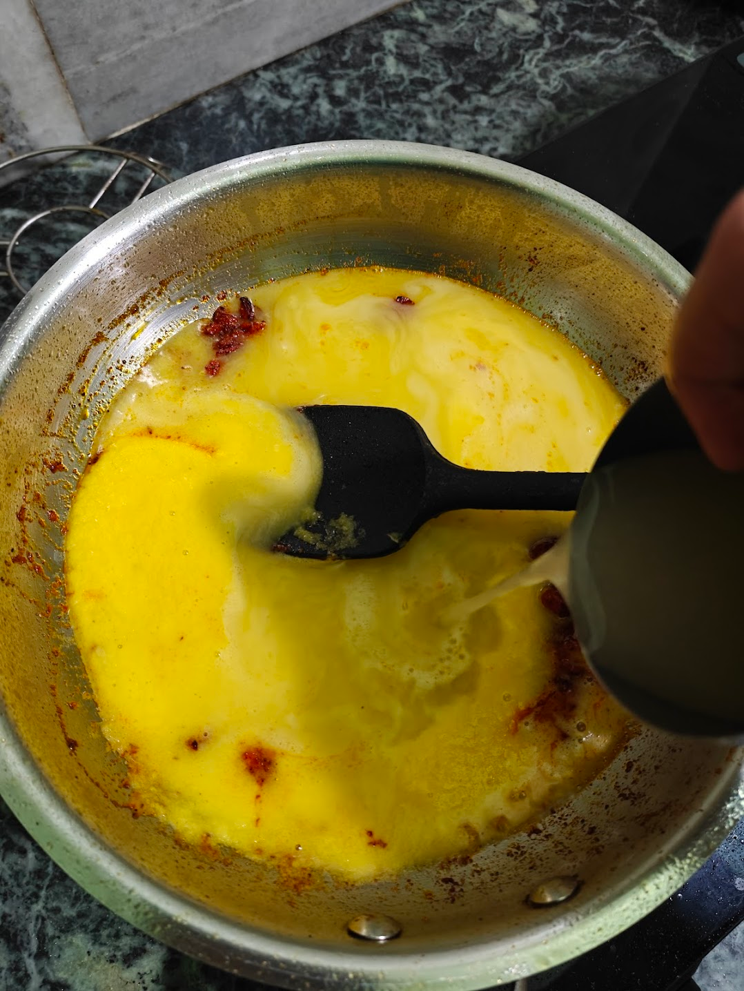 Water being poured into the mango soup mixture to adjust consistency