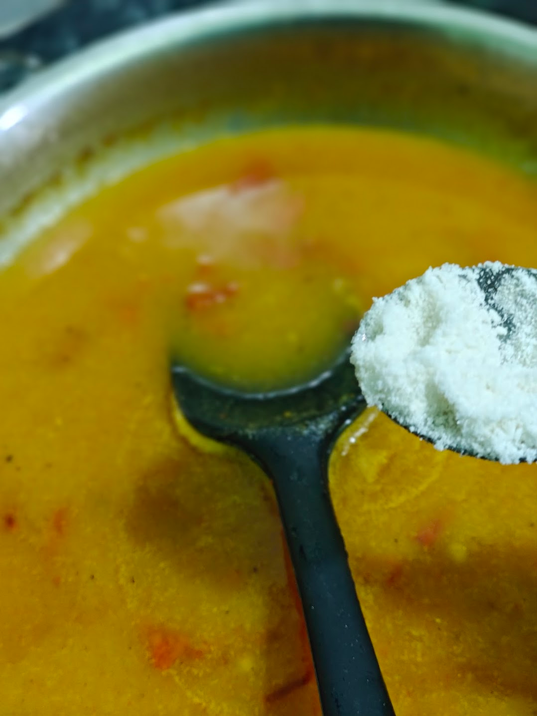Powdered sugar being added to balance the tangy mango soup